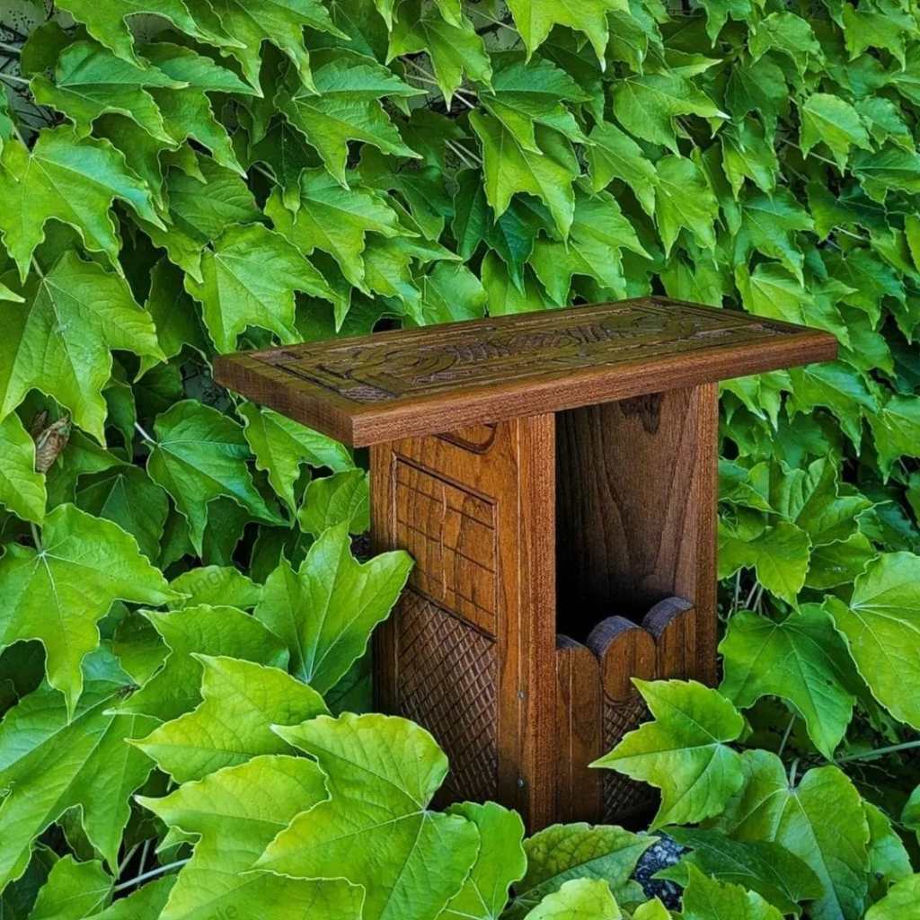 Un banc en bois décoratif situé devant un mur de feuilles vertes luxuriantes.